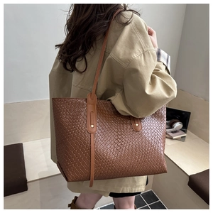 Close-up of the woven texture and leather strap on this large brown tote bag