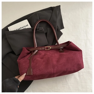 Detail view of burgundy faux suede tote bag with brown leather strap and gold buckle