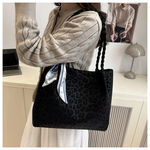 Detail of leopard print tote bag with thick black woven handles and decorative silk scarf