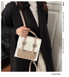 Detail of a beige contrast tote bag featuring star metal accents and smooth synthetic leather