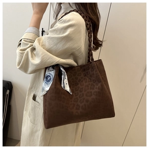 Detail view of leopard print tote bag with woven strap and silk scarf accessory