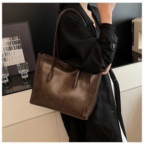 Dettaglio della borsa tote vintage marrone con cuciture a vista e tracolla sottile elegante