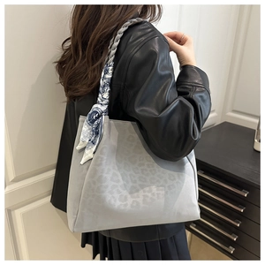 Detail of vintage leopard print tote bag with woven handles and silk scarf on a model