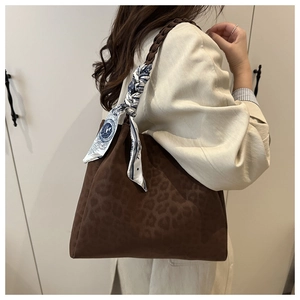 Detail of leopard print tote bag with woven handle and blue decorative scarf accessory
