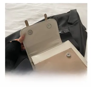 Détail des fermoirs magnétiques et du logo de marque sur un sac à bandoulière bicolore