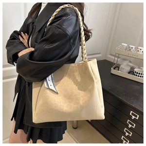 Detail of cream tote bag featuring thick braided handle and decorative geometric silk scarf