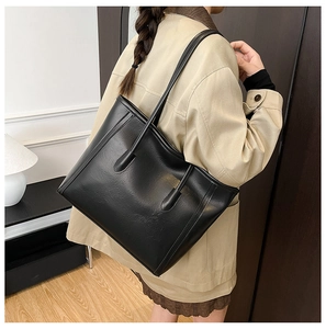 Dettaglio di una grande borsa tote nera vintage su un modello con un trench coat