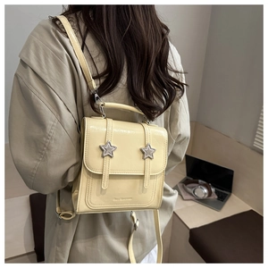 Détail du sac à dos en cuir verni crème avec boucles étoiles et design de sangle