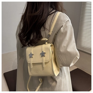 Détail d'un mini sac à dos jaune en similicuir avec boucles étoiles et logo gravé