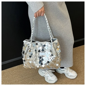 Detail shot of a silver sequined tote bag featuring large round sequins and woven handles