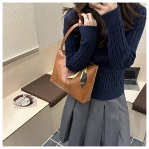 Brown faux leather tote bag with decorative scarf displayed in a cozy lifestyle setting