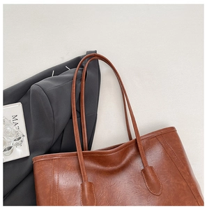 Dettaglio della borsa tote in ecopelle marrone scuro con cuciture rinforzate e lucide