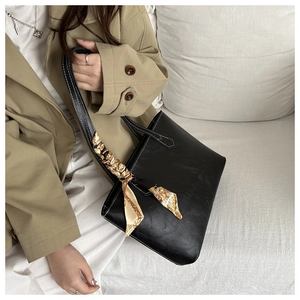 Detail of black pebbled tote bag with contrast stitching and silk scarf handle accent