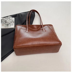 Vista dettagliata della borsa tote marrone scuro in pelle testurizzata vintage con manici lunghi