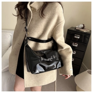 Détail d'un sac hobo noir chic avec boucle argentée sur un lit minimaliste élégant