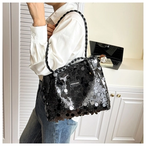 Detail of black sequined shoulder bag featuring a hand-woven leather handle and logo tag