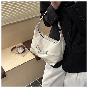 Détail du sac hobo avec boucle et chaîne argentée porté par un mannequin en costume