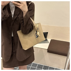 Khaki leather tote bag with silk scarf detail shown in a minimalist office setting