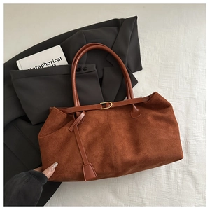 Macro shot of brown suede tote bag featuring smooth leather handles and gold metal buckle