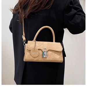 Detail view of the silver clasp and leather fashion charm on a khaki shoulder bag