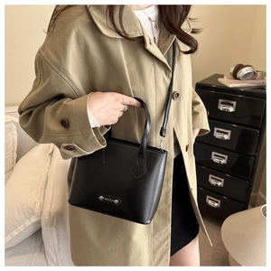 Detail of minimalist black leather tote bag with silver Fashion metal plate and handle