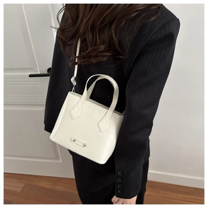 Detail of elegant cream white bucket bag with leather texture and fashion metal logo