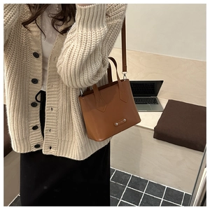 Brown leather bucket bag detail with double handles and detachable strap for office style