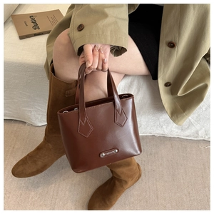 Detail of brown leather handbag with metallic fashion plaque on a stylish autumn outfit