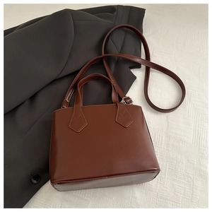 Detailed view of dark brown PU leather handbag with fine stitching and shoulder strap