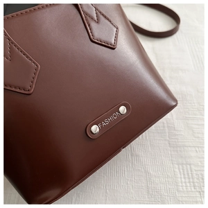 Close-up of dark brown leather handbag with silver metallic Fashion plate and fine stitching