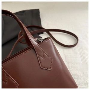 Detailed close-up of dark brown leather tote bag with fine stitching and silver buckle
