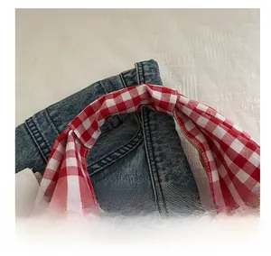 Detailed close-up of the red and white checkered handle strap on a denim tote bag