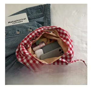 Detail showing red plaid tote bag capacity with smartphone, wallet, and cosmetics inside