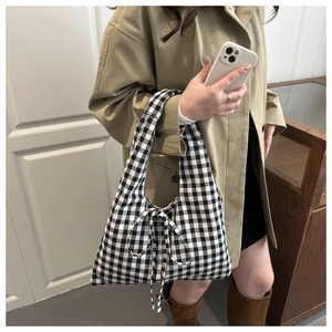 Sac cabas en toile à carreaux noir et blanc avec nœud papillon porté par un mannequin