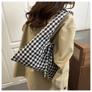 Detailed view of black and white gingham shoulder bag with decorative bow on a model