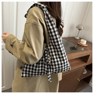 Detailed view of black and white gingham canvas tote bag styled with a khaki trench coat