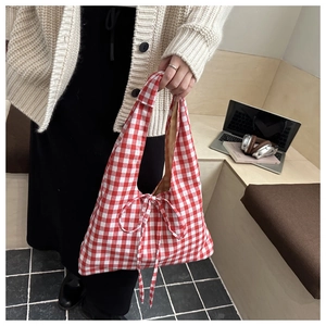 Close-up of red and white plaid tote bag featuring a decorative bow tie and fabric texture