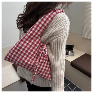 Détail d'un grand sac cabas à carreaux rouges et blancs avec nœuds latéraux
