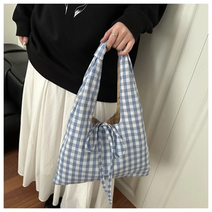 Detail of blue and white gingham fabric tote bag with a bow tie closure on top