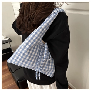 Detail of blue and white gingham canvas shoulder bag showing soft fabric texture and strap