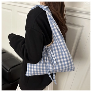 Close-up of blue and white gingham tote bag featuring a decorative side bow detail