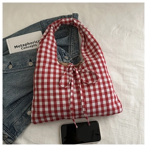 Vue détaillée du sac cabas à carreaux rouges avec nœud, veste en jean et mobile