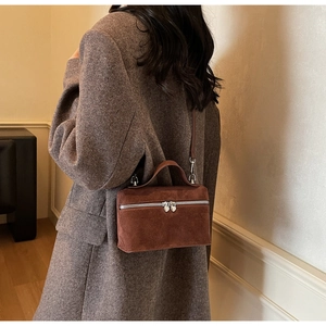 Détail du sac bandoulière en daim marron avec doubles fermetures éclair en forme de cœur