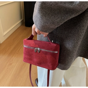 Detail der roten Wildledertasche mit silbernen Reißverschlüssen und Herz-Anhängern
