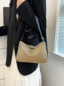 Elegant gold rhinestone hobo shoulder bag with black strap styled on a model