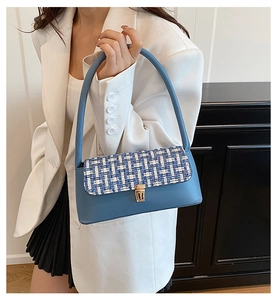 Detail of blue faux leather shoulder bag with textured tweed flap and gold metal buckle
