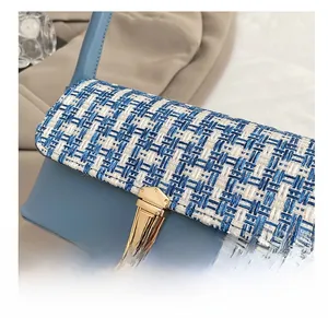 Macro detail of the blue tweed flap with a high-quality gold metal clasp on a shoulder bag