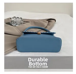 Detailed macro view of the durable bottom with contrast stitching on blue leather handbag