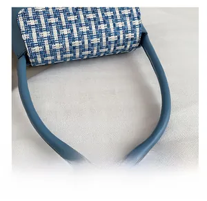 Detailed close-up of blue leather handbag with tweed texture and thick tubular shoulder strap