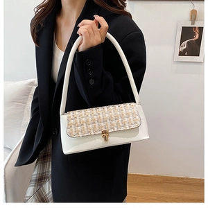 Close-up of a white leather underarm bag with tweed flap and gold metal twist lock